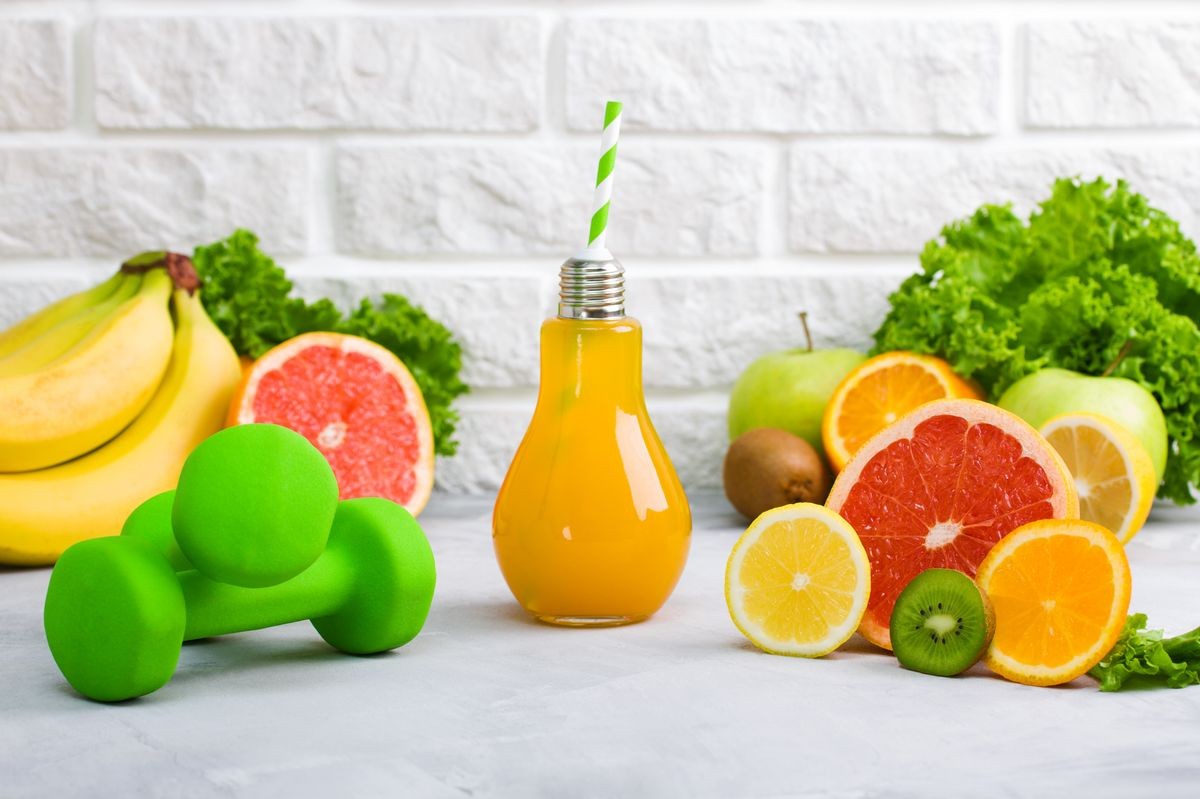 Concept healthy eating, diet plan, detox, drinks, sports nutrition ideas. Beverage in lamp glass, fruits grapefruit, lemon, kiwi, apple, banana, green salad and sport equipment green dumbbells.